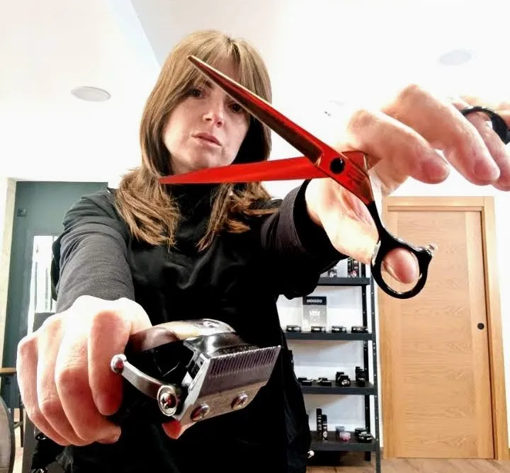 La barbera de Peliños con unas tijeras rojas y la máquina de cortar