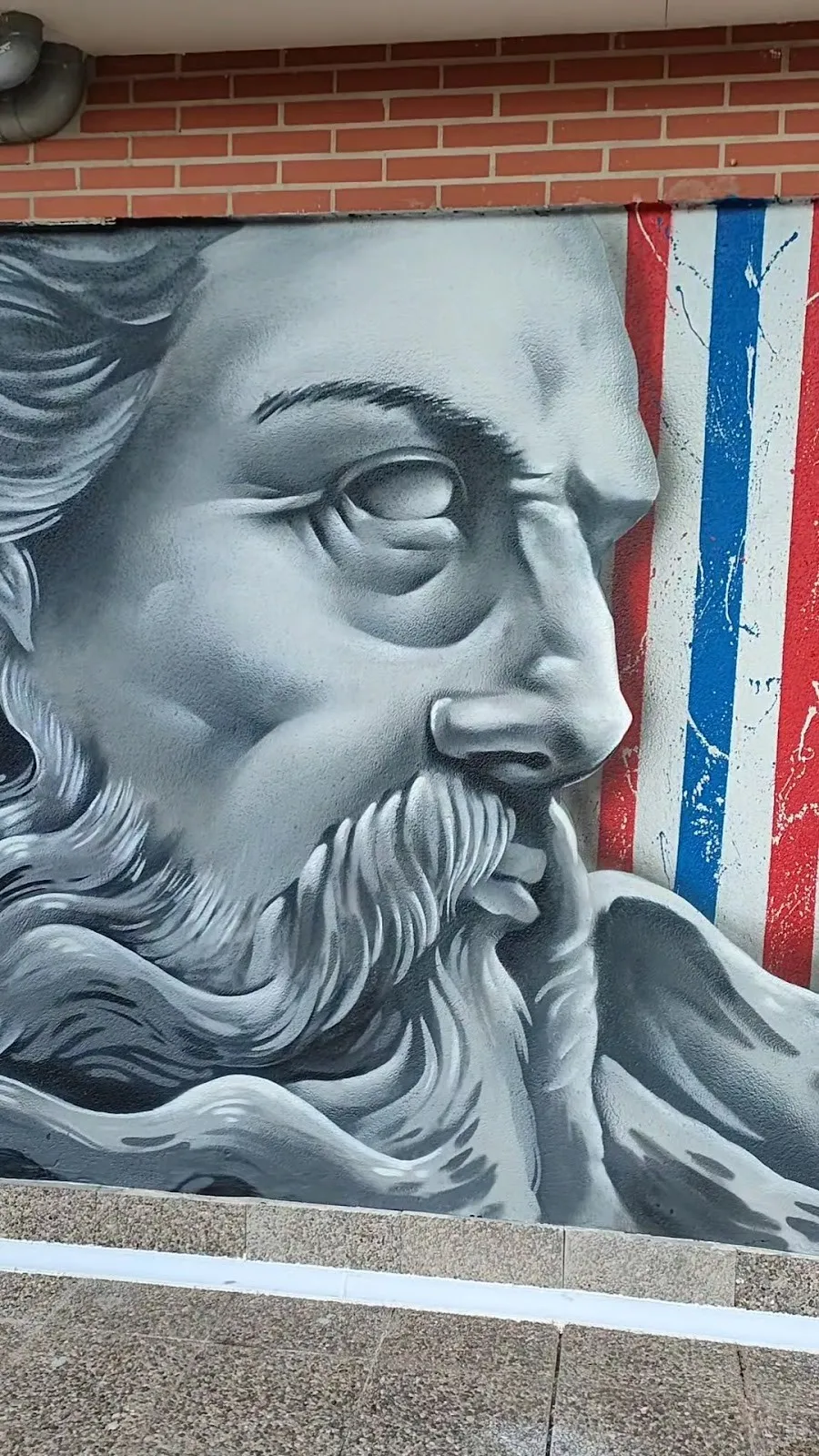 Mural de un dios griego barbudo con franjas de poste de barbero en la fachada